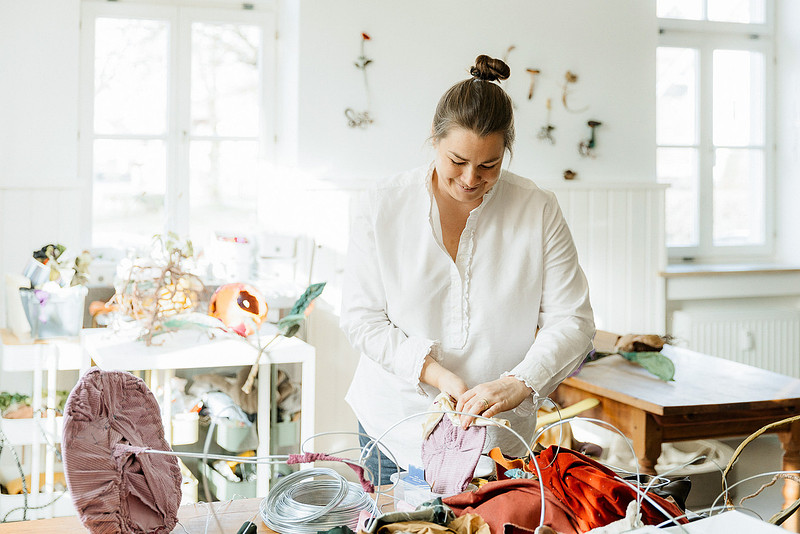 B2B-Fotografie für Kreative: Bildhauerin Anne Carnein arbeitet fokussiert an einem neuen Kunstwerk an ihrem Arbeitstisch.