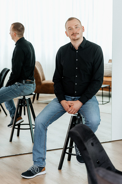 Brandingfotografie Ravensburg Mann sitzt auf Barhocker vor einem Spiegel im Studio, Businessfotograf Ravensburg